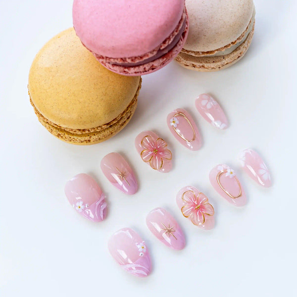 Lifestyle shot press on nails Petali Danzanti con macarons rosa, mostrando effetto cat-eye magnetico e decorazioni 3D luxury con eleganza francese