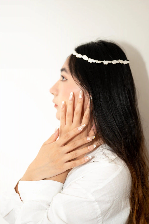 Donna con capelli raccolti mostrando press on nails Margherite Delicate, eleganza classica con margherite dipinte a mano artigianale italiana