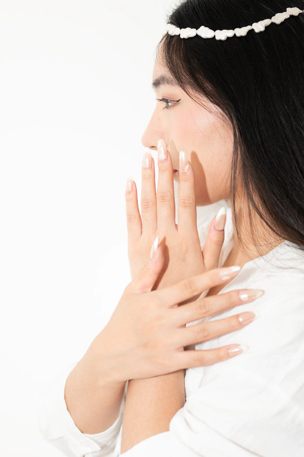 Lifestyle shot donna elegante con camicia bianca e press on nails Margherite Delicate, mostrando nail art dipinta a mano con french sfumato romantico