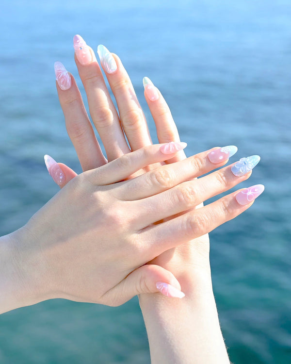 Lifestyle shot mare con acqua cristallina, mostrando press on nails Dolci Sussurri Floreali con sfumature pastello azzurro e decorazioni floreali delicate romantico estivo