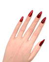 Mano con dita piegate mostrando press on nails Rosso Seducente Christmas edition, effetto specchio magnetico cromato ultra-brillante per party natalizi
