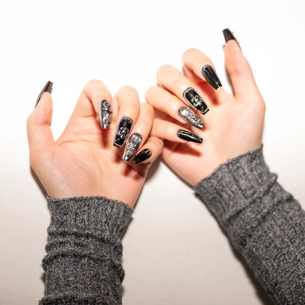 Mani sovrapposte con nail art gotica nera e argento, press-on nails di qualità